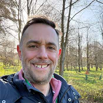 Sam Cremnitz standing in woods in the sunshine