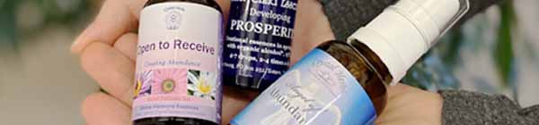 Three bottles of Abundance Essences held in a hand