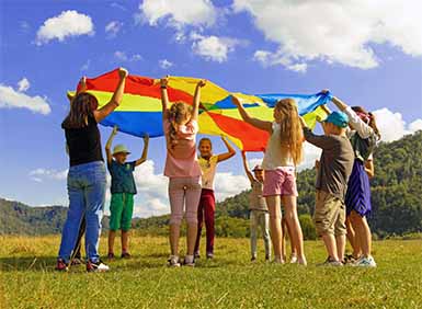 A picture of a group of children playing with colourful material in a field