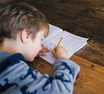 A school child writing in a school work book