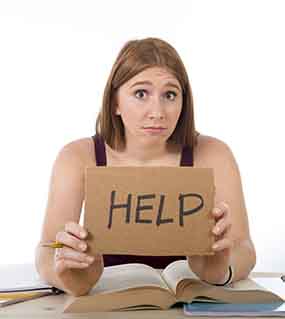 A young lady holding a sign saying help over school text book