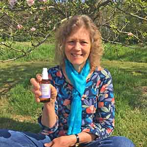 Catherine sitting on grass with a Strength & Courage spray Essence