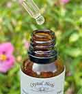 A Crystal HerbsBach Flower Remedy comination bottle and pippette with flowers in the background