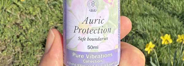 A bottle of Auric Protection Essence spray held in a hand
