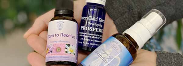 Three bottles of Abundance Essences held in a hand