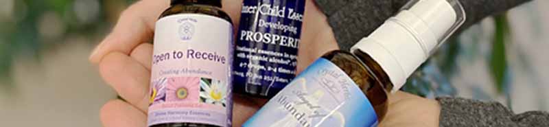 Three bottles of Abundance Essences held in a hand